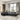 Modern black leather sectional sofa with reclining feature, set in a bright living room with large windows and contemporary decor.