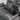 Close-up of the grey leather recliner's center console with two cup holders, a hidden storage compartment with a hinged lid, and quilted fabric details on the seat.